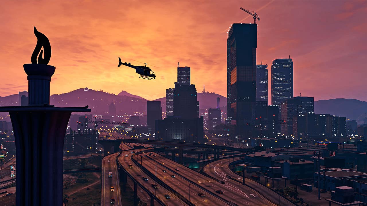 A snapshot of the skyline in GTA Online at the time of sunset while a helicopter flies by in the center.