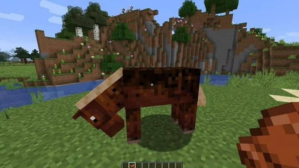 Horse and a saddle in the player's hand in Minecraft.